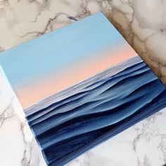 an acrylic painting of the ocean on a marble countertop with blue and pink colors