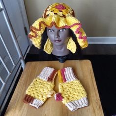 a crocheted hat and mittens are sitting on a table next to a mannequin's head