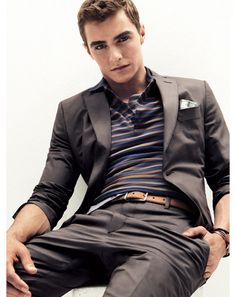 a young man sitting on top of a white chair wearing a suit and striped shirt