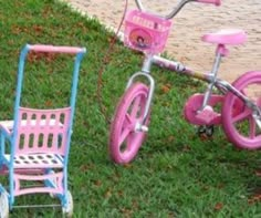 two pink and blue children's bikes sitting in the grass next to each other