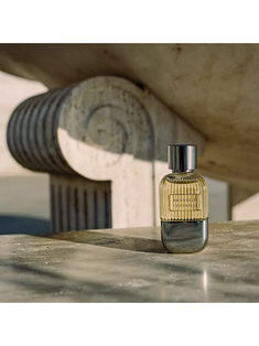 a bottle of perfume sitting on top of a wooden table next to a concrete structure