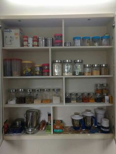 an open cupboard filled with lots of different types of food and containers on it's shelves