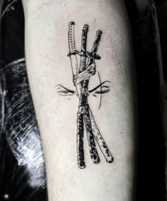 a black and white photo of a tattoo with two knives tied to each other on someone's arm