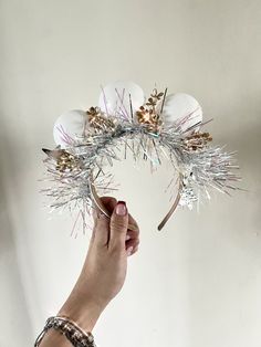 a person is holding up a wreath made out of white balls and tinsels