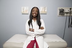 a woman sitting on top of a white bed in a room with blue walls and two telephones