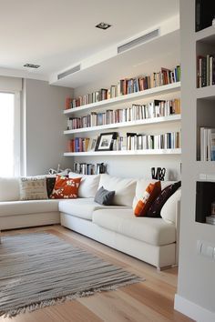 a living room filled with lots of white furniture and bookshelves full of books