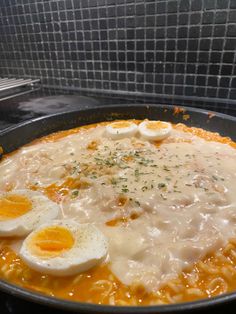 eggs are being cooked on top of noodles in a skillet with gravy