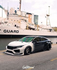 a white car parked in front of a large ship