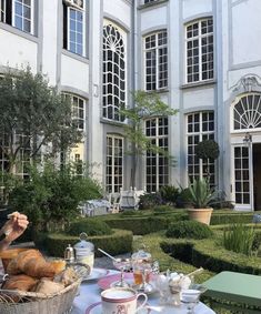 a woman sitting at a table with food and drinks in front of a large building