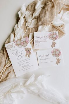 the wedding stationery is laid out on top of some feathers and paper with teddy bears