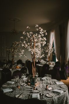 a dining room table set with place settings and flowers in vases on the tables