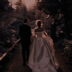 a bride and groom walking down a path