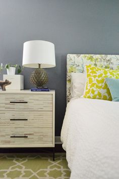 a white bed sitting next to a nightstand with a lamp on top of it