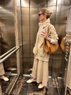 a woman is taking a selfie in the elevator with her cell phone and purse