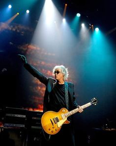 an image of a man that is on stage with his arms out and guitar in the air