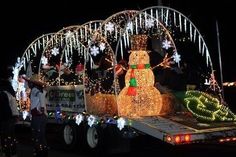 a truck decorated with christmas lights and snowmen on it's flatbed at night