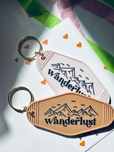 two keychains with the words wanderlust on them and mountains in the background