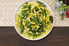 a white bowl filled with broccoli and nuts on top of a wooden table