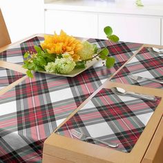 a plaid table cloth with flowers and cutlery on it in front of a window