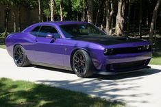 a purple and black car is parked on the side of the road in front of some trees