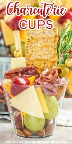 a glass bowl filled with cheese, crackers and fruit on top of a table