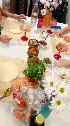 several people sitting at a table making pizzas and condiments for each other