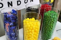 candy and candies are displayed in glass vases on a table with london sign