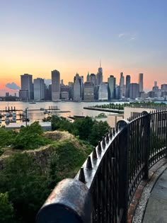 an iron fence overlooks the city skyline at sunset