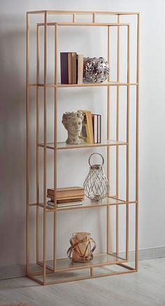 a book shelf with books and vases on it in front of a white wall