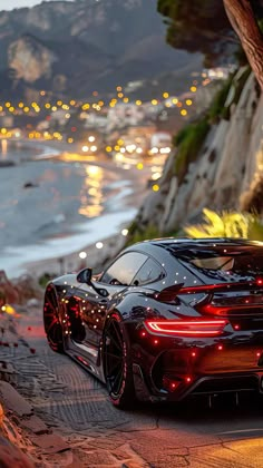 a black sports car parked on the side of a road next to a body of water