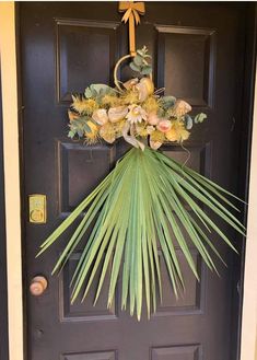 a front door decorated with flowers and palm fronds, hanging from the side