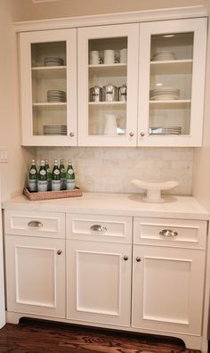 a kitchen with white cabinets and glass doors on the cupboards is pictured in this image