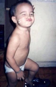 a young boy in diapers standing on top of a wooden floor