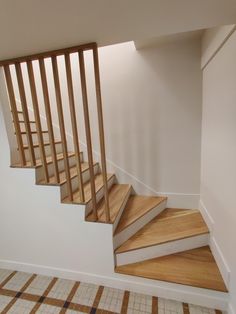 there is a stair case in the corner of this room with tile flooring and wooden handrails