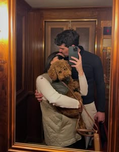 a man and woman taking a selfie in front of a mirror with a dog