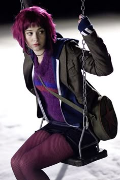 a woman with pink hair sitting on a swing