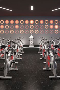 there are many exercise bikes in the gym with red and white circles on the wall