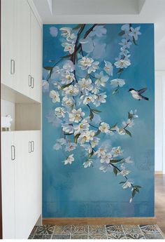 a painting of white flowers on a blue wall in a room with wooden flooring