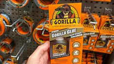 someone is holding up a gorilla glue in front of some orange and black items on the shelf