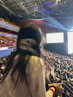 a woman is standing in front of an auditorium full of people with head coverings