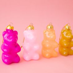 three gummy bears are sitting next to each other on a pink background with gold accents