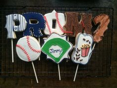 decorated cookies are sitting on a rack with baseballs, mitts, and letters