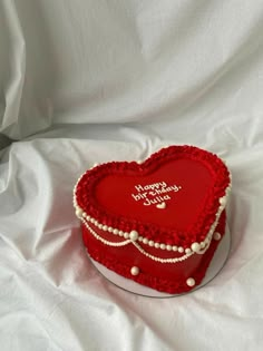 a red heart shaped cake with pearls on it