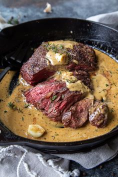 a steak dish in a cast iron skillet with mustard sauce and potatoes on the side