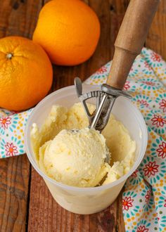 an ice cream in a bowl next to two oranges