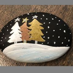 a painted rock with trees and snow on it