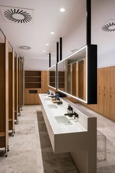 a row of sinks in a public restroom with mirrors and lights on the wall above them