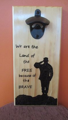 a wooden plaque with an image of a man holding a bottle opener and the words, we are the land of the free because of the brave