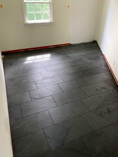 an empty room with black tile flooring and white walls