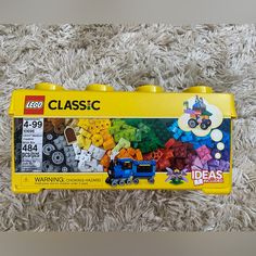 a yellow lego box filled with lots of different colored blocks and toys sitting on top of a white carpet